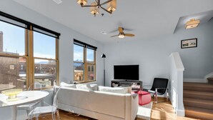 Een moderne woonkamer met een bank, televisie en een eethoek.