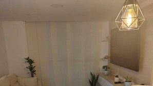 A modern living room with a sofa, a dining table with placemats, a wooden cabinet, and a hanging light fixture. - New apartment well located in a 4 floor brand new with all the comforts. (Barranquilla)
