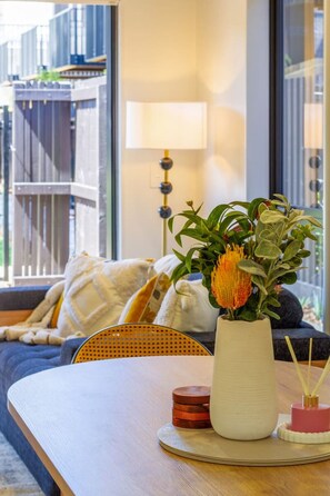 Ein modernes Wohnzimmer mit einer Couch, einem Couchtisch, einer Vase mit Blumen und einer Lampe.