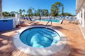 A circular hot tub with a pool in the center, surrounded by lounge chairs and a white fence. - MINT Julip - Amazing 40+ Community - Newly Updated 2 bed/2 bath single family (Largo)
