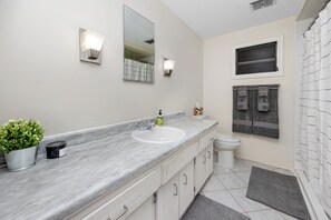 A bathroom with a marble countertop, a sink, a toilet, a shower curtain, and a small potted plant. - MINT Julip - Amazing 40+ Community - Newly Updated 2 bed/2 bath single family (Largo)