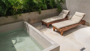 A spa area with a rectangular hot tub and two wooden lounge chairs with beige cushions. - Luxury Penthouse in Tulum with Private Rooftop (Tulum)