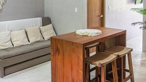 A modern living room with a wooden coffee table and two bar stools, a grey sofa with cushions, and a wooden door. - Luxury Penthouse in Tulum with Private Rooftop (Tulum)