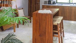 A modern kitchen with wooden cabinetry, a built-in microwave, and a window with a view. - Luxury Penthouse in Tulum with Private Rooftop (Tulum)