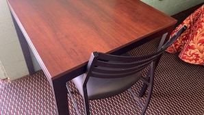 A wooden table with a chair, a patterned carpet, and a green wall.