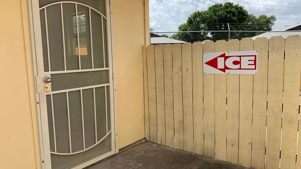A gated entrance with a metal door and a wooden fence.