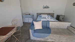 Un dormitorio con cama, una silla, una mesita y un adorno en la pared.