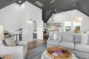 A modern living room with a grey sofa, a dining area, and a kitchen. - High dunes of Bramble Reach cottage with ocean views (Bald Head Island)
