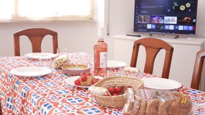 Une table à manger dressée avec des assiettes, une bouteille et un panier de pain.