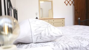 Une chambre à coucher avec un lit, une commode, un miroir et une porte.