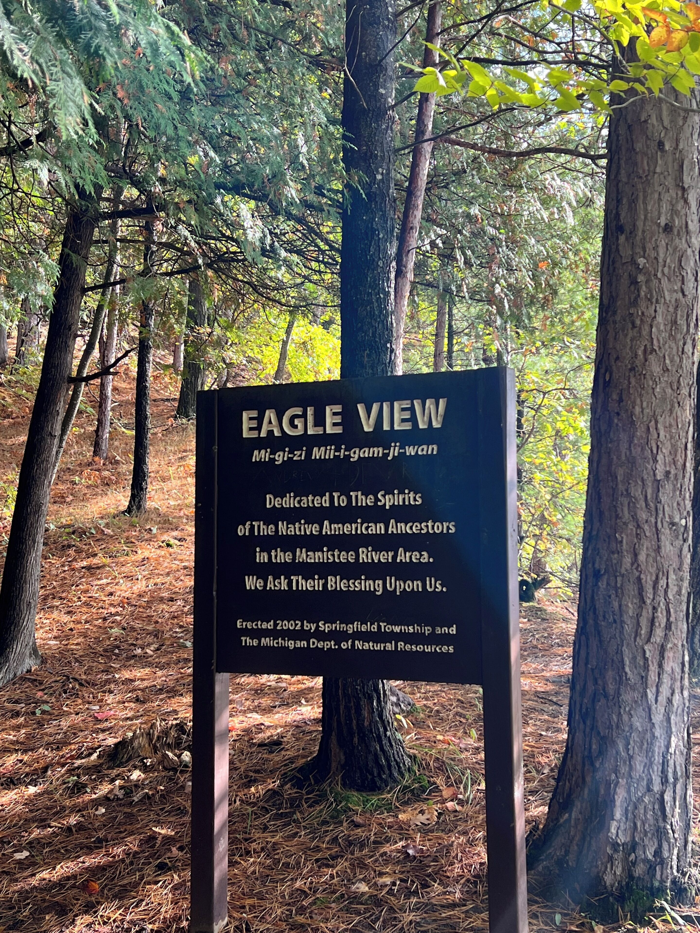A sign dedicated to Native American ancestors in a forested area.