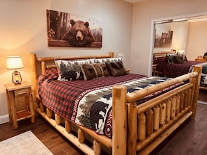 A wooden bed with a quilt, a bedside lamp, and a bear-themed pillow.