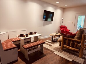 A compact living space with a dining area, a red armchair, and a television mounted on the wall.