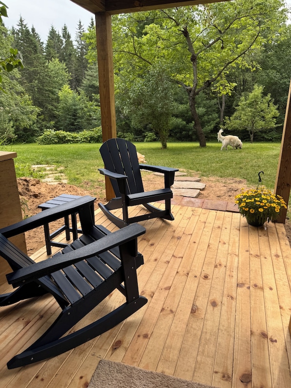 Terraza de madera con sillas Adirondack y una planta en maceta.