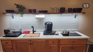 Une cuisine avec des meubles de rangement en bois, un plan de travail, une machine à café et une plante suspendue.