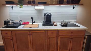 Une cuisine avec des meubles de rangement en bois, un plan de travail, une machine à café et une plante suspendue.