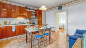 Una cocina moderna con armarios de madera, una mesa de comedor con sillas y un sofá azul en la sala de estar.