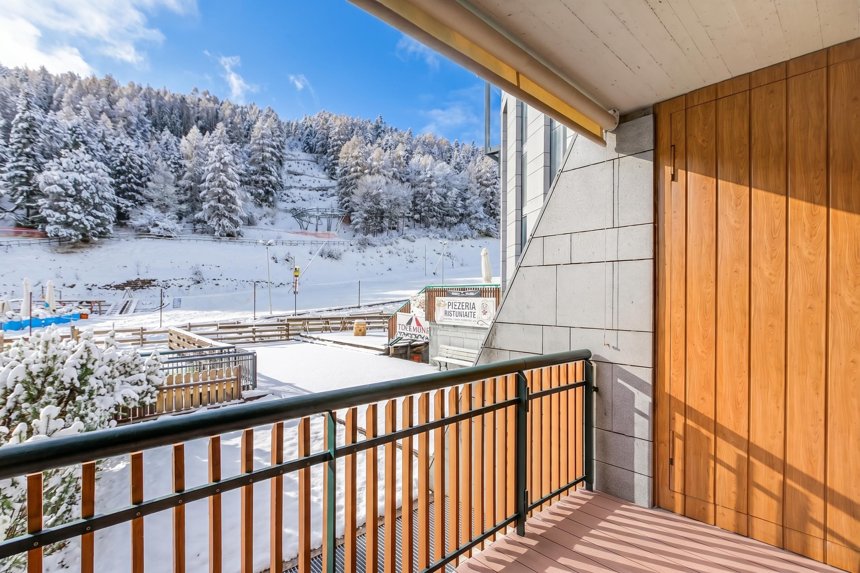 A balcony with a view of a snowy landscape and a sign for a local establishment.