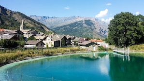 Un borgo sul lago con edifici tradizionali, una chiesa e montagne sullo sfondo.