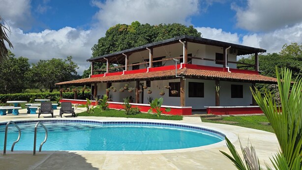 A two-story house with a swimming pool, surrounded by greenery and a clear sky. - Resting farm : Plumavera Doradal Reserve (Doradal)