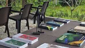 A table with several bird books and a bird sculpture in a natural setting. - Resting farm : Plumavera Doradal Reserve (Doradal)
