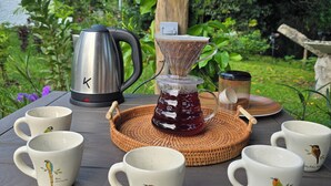 A table set outdoors with a coffee maker, a glass carafe, and several mugs with bird designs. - Resting farm : Plumavera Doradal Reserve (Doradal)