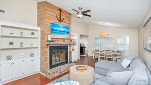 A spacious living room with a fireplace, a ceiling fan, and a dining area with a table and chairs. - Coastal Comfort- Intracoastal Waterway Escape (Murrells Inlet)