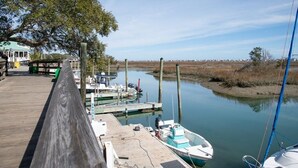 A wooden dock with boats, a covered area, and a calm water body. - Coastal Comfort- Intracoastal Waterway Escape (Murrells Inlet)