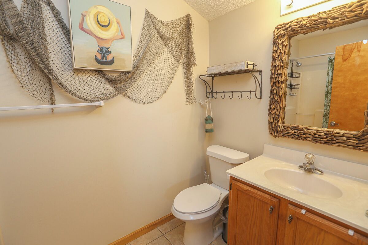 Une salle de bain avec des toilettes blanches, un meuble en bois, un lavabo avec un miroir et un espace douche.