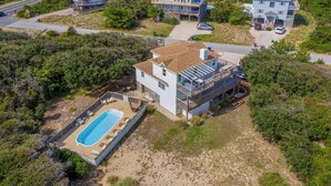 A two-story house with a pool, surrounded by dense vegetation and a clear sky. - Absolute Paradise -  4 BR Oceanside Home w/Private Pool, 105 Yards to Beach Access (Southern Shores)
