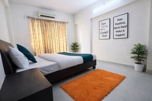 A modern bedroom with a bed, a nightstand, a potted plant, and motivational wall art.
