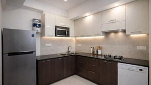 Una cucina moderna con elettrodomestici in acciaio inossidabile, mobili in legno scuro e un pannello di divisa in piastrelle bianche.