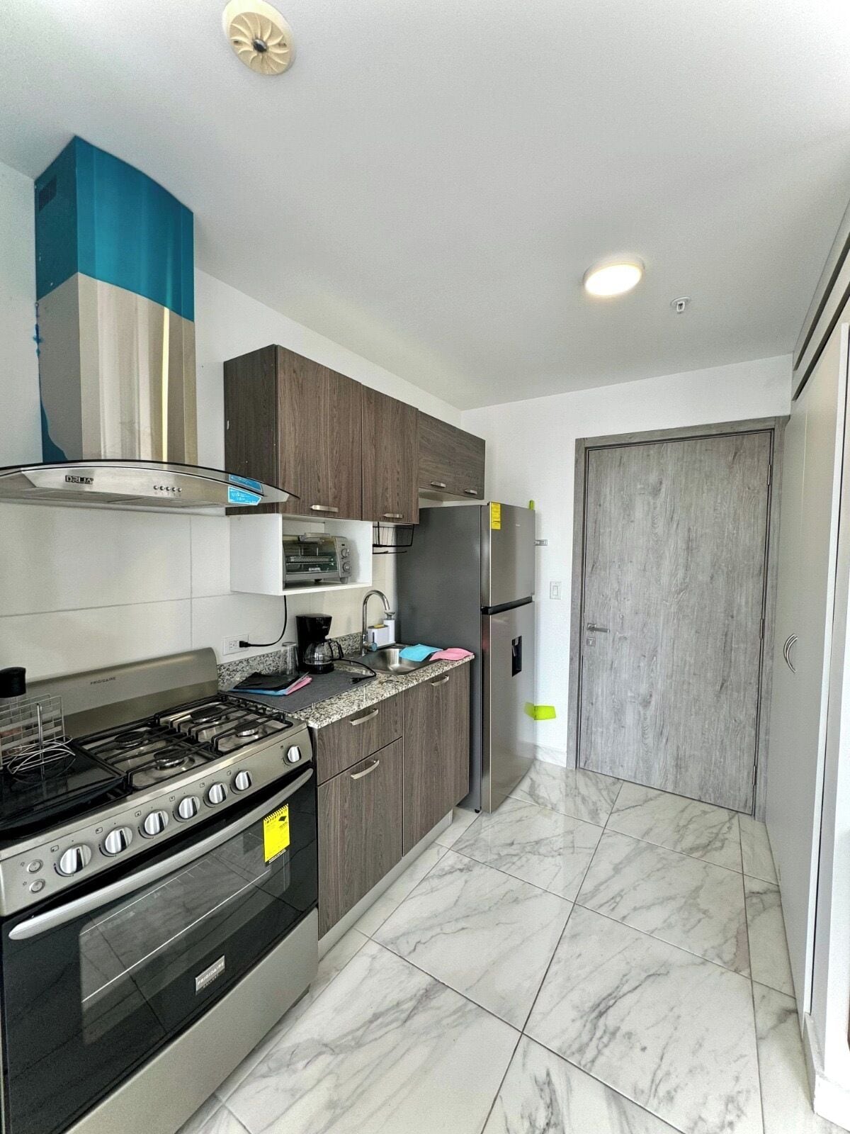 Una cocina moderna con estufa a gas, horno, microondas y refrigerador de acero inoxidable.