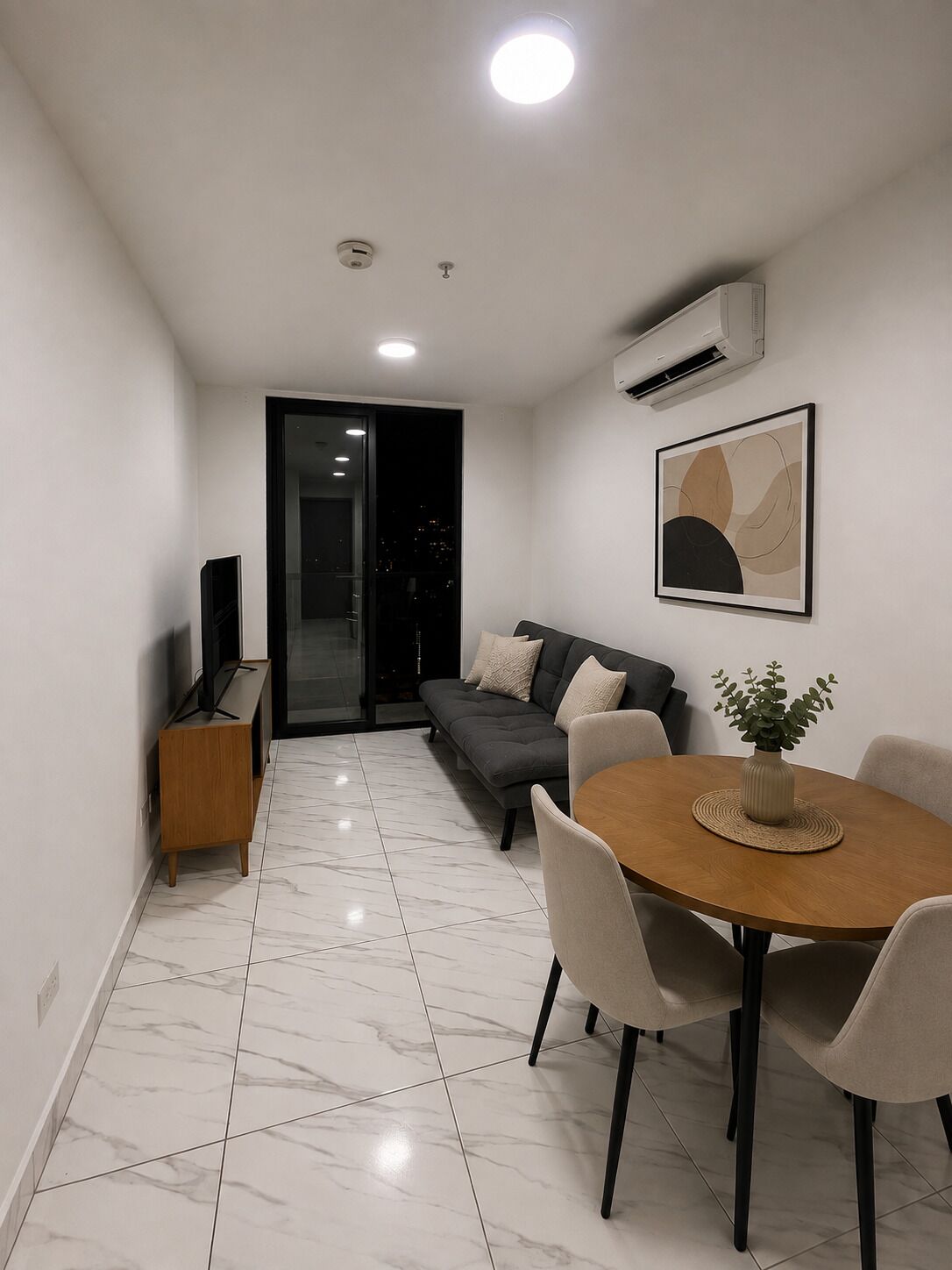 A modern living space with a dining area, a sofa, and a television.