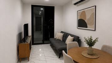 A modern living space with a dining area, a sofa, and a television.