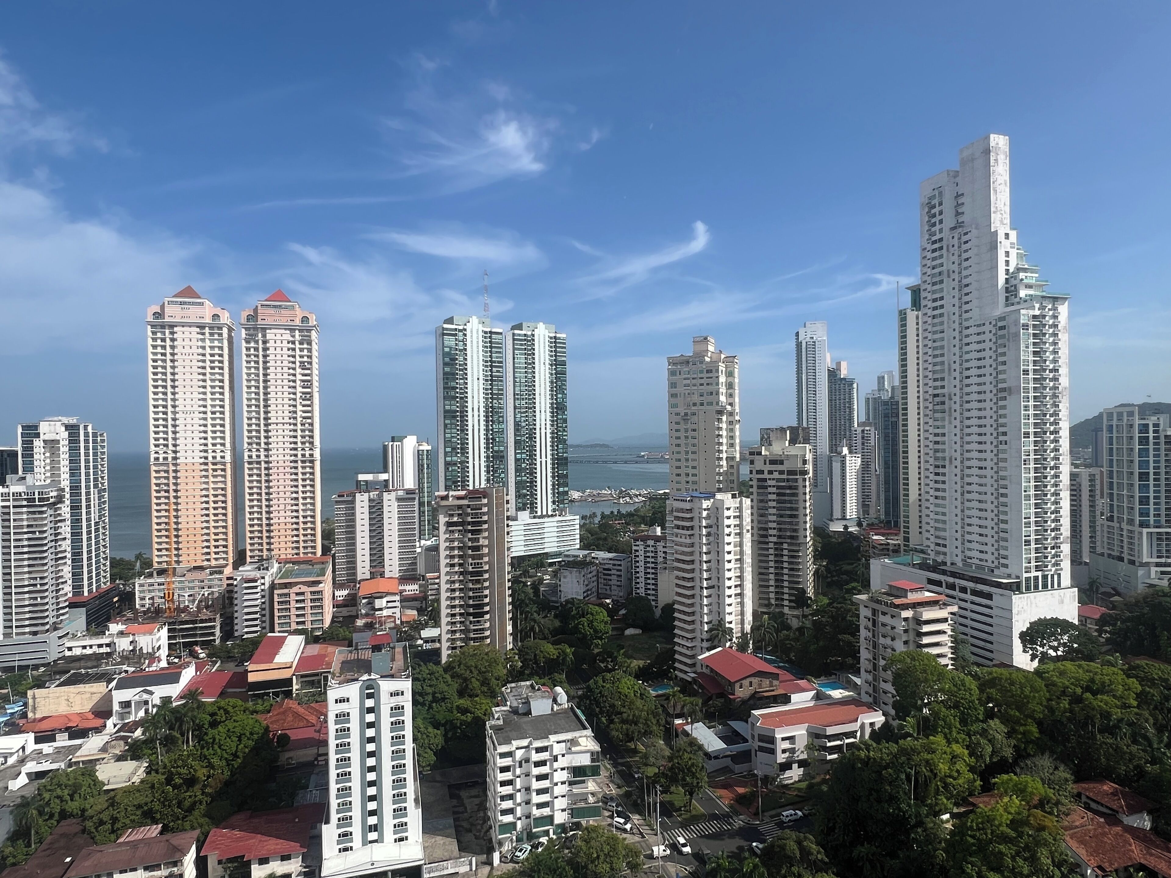 Un paisaje urbano con rascacielos, cielo despejado y una masa de agua al fondo.
