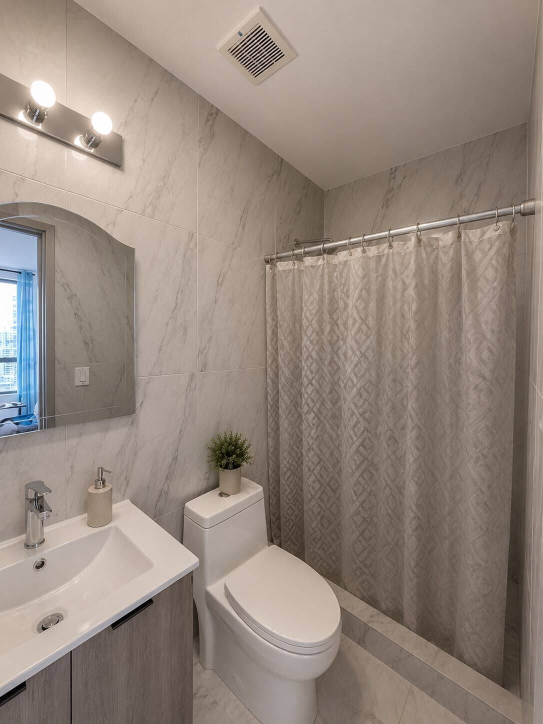 A bathroom with a white sink, a toilet, a shower curtain, and a mirror.