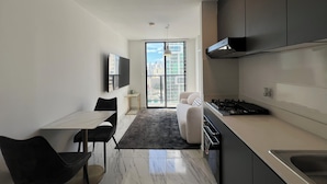 Una cocina moderna con comedor, televisor de pantalla plana y vistas a la ciudad a través del ventanal.