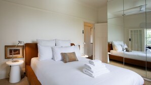 Una habitación de hotel con una cama grande, una mesita de noche con una lámpara, un cuadro en la pared y un espejo.