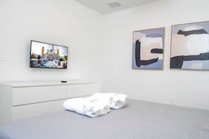 A hotel room with a bed, a flat-screen TV mounted on the wall, and abstract art pieces on the wall. - Family Villa Private Pool Spa Arcade Sleeps 22 (Davenport)
