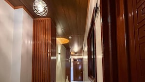 A hallway with wooden paneling, a hanging light fixture, and a door with a geometric pattern. - Hotel Yagua Iquitos (Belen)