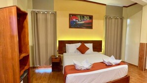 A hotel room with a wooden bed, a nightstand, a wooden wardrobe, and a painting on the wall. - Hotel Yagua Iquitos (Belen)