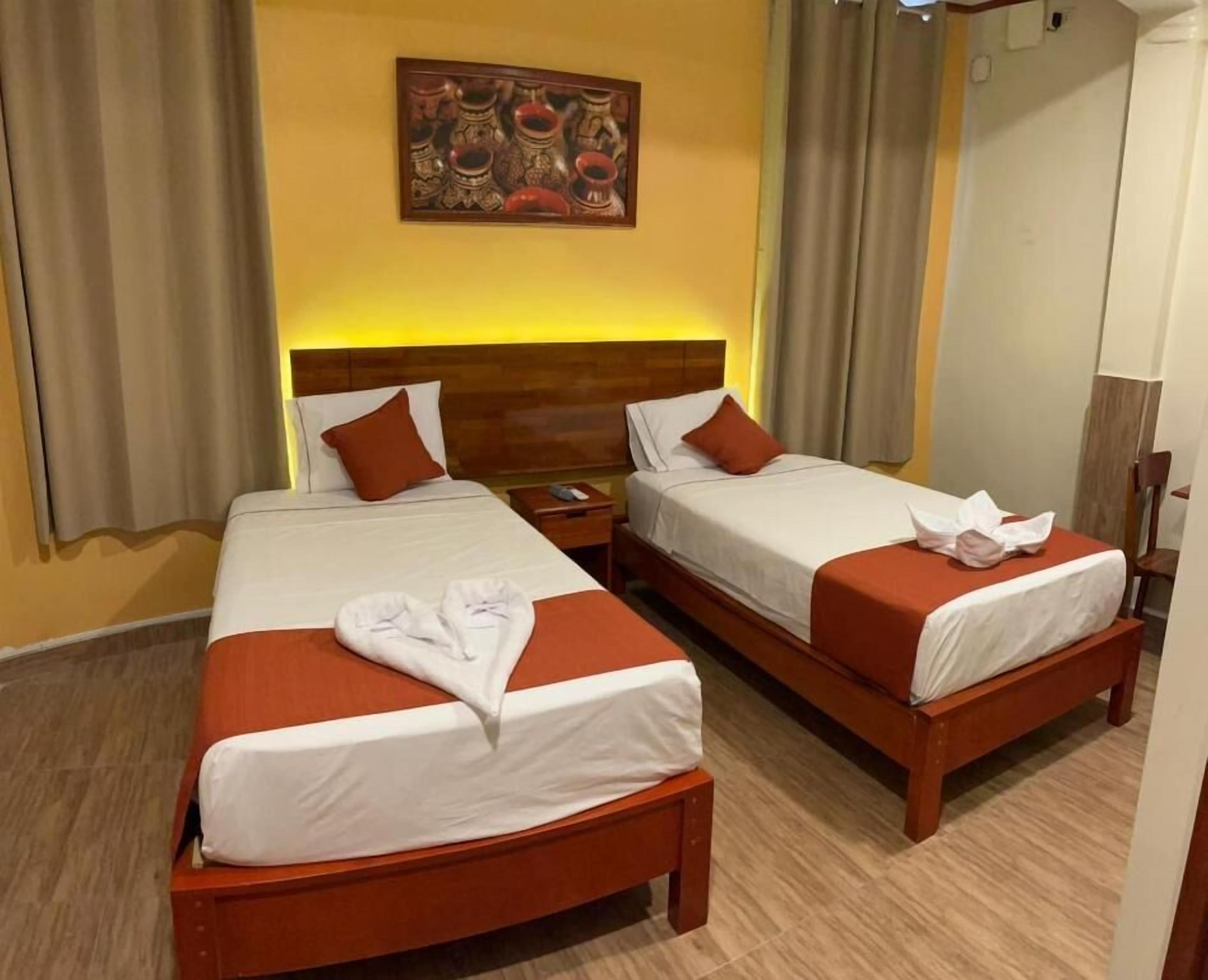A hotel room with two beds, wooden headboards, and a painting on the wall.