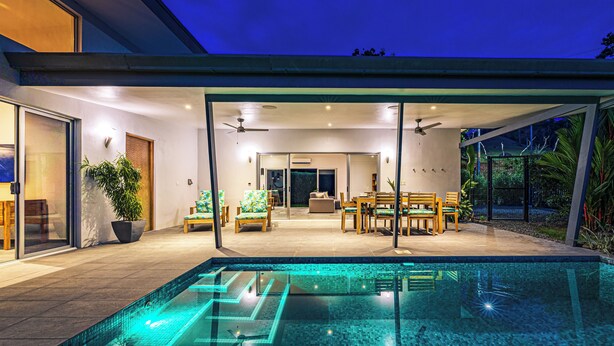 A modern house with a swimming pool, a dining area, and a patio.