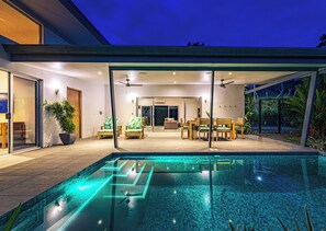 Ein modernes Haus mit Pool, Essbereich und Terrasse.