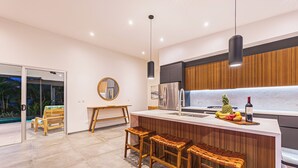 A modern kitchen with a wooden island, stainless steel appliances, and a fruit bowl.