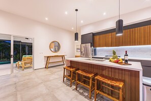 A modern kitchen with a wooden island, stainless steel appliances, and a fruit bowl. - Uvita • Modern Villa •Mountains & Ocean • Private Pool + Sunset Views (Uvita)