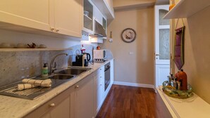 A compact kitchen with white cabinets, a stainless steel sink, a coffee maker, and a microwave. - Casa Orta apartment with lake view (Orta San Giulio)