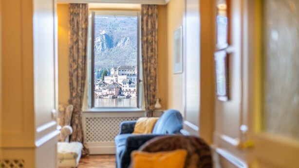 A hotel corridor with a view of a mountainous town through a window. - Casa Orta apartment with lake view (Orta San Giulio)