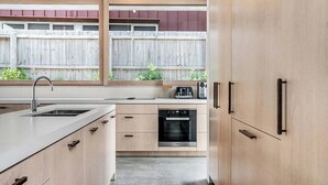 Een moderne keuken met een inbouwoven, een spoelbak en houten kastjes.